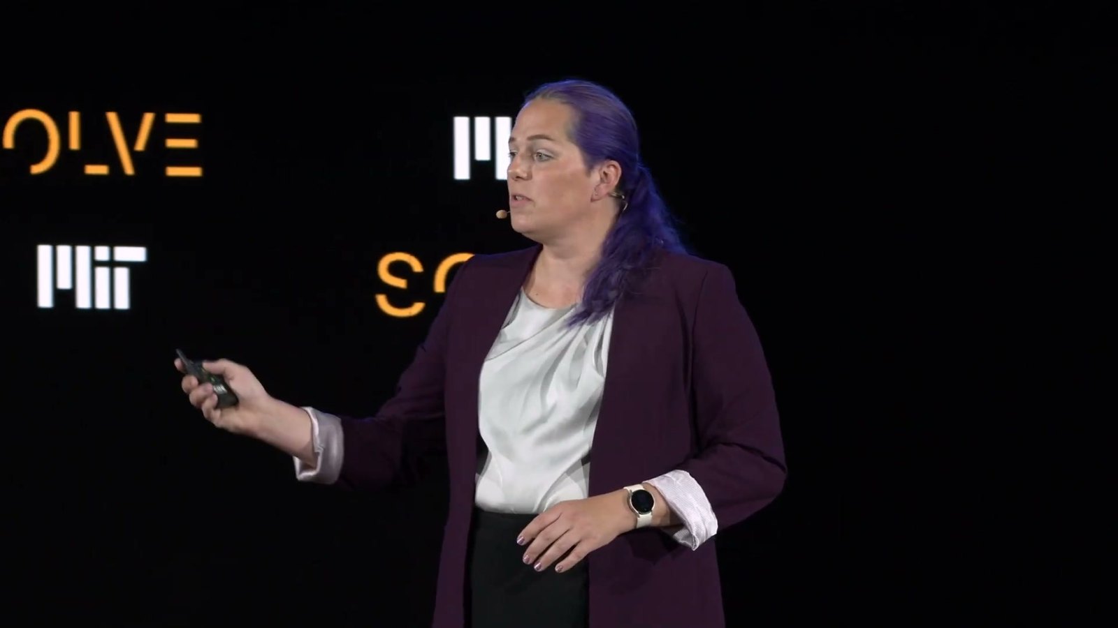 Jessica Hicklin presenting on stage at MIT Solve, holding a clicker, with the MIT and Solve logos behind her.