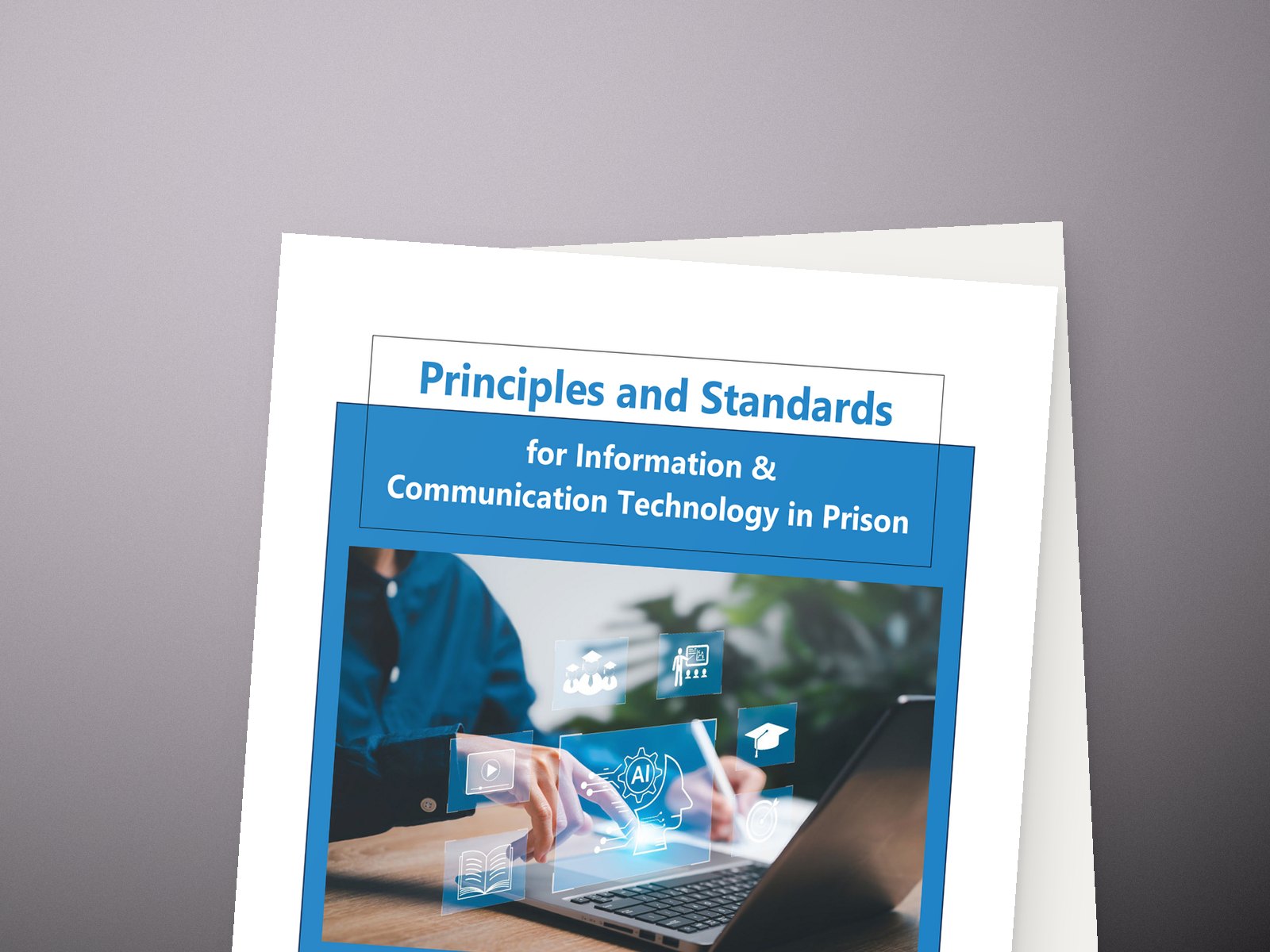 The cover of Principles and Standards for Information and Communication Technology in Prison, resting on a desk.