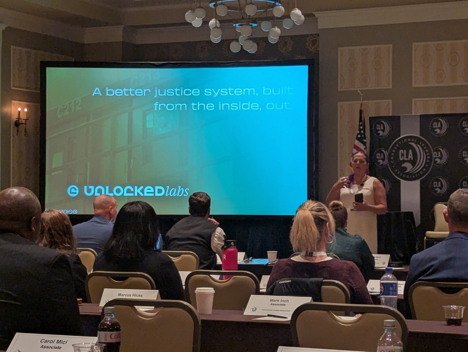 Jessica Hicklin speaking at a Correctional Leaders Association event beside a presentation slide.