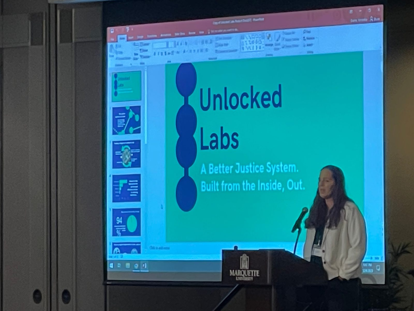 Jessica Hicklin at a podium at Marquette University in front of a projected slide.