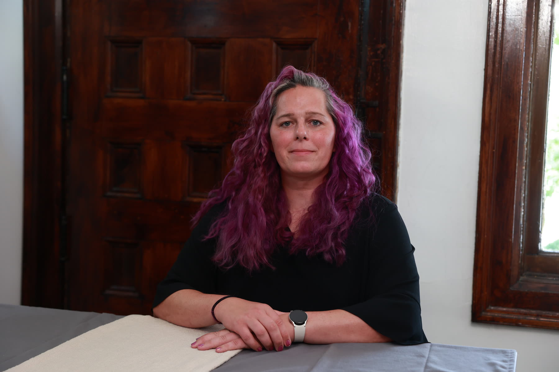 Jessica Hicklin seated at a table in front of a carved wooden door.